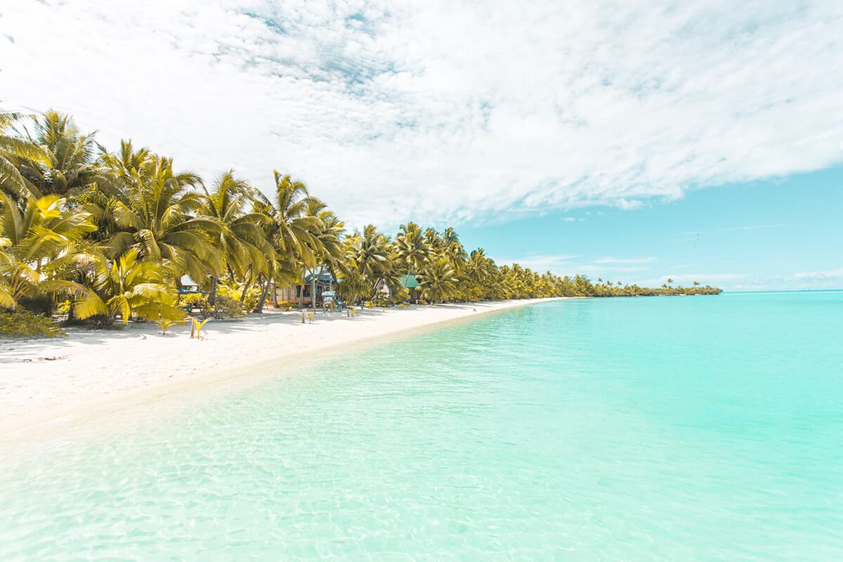 a beach in aitutaki with blue water and white sand