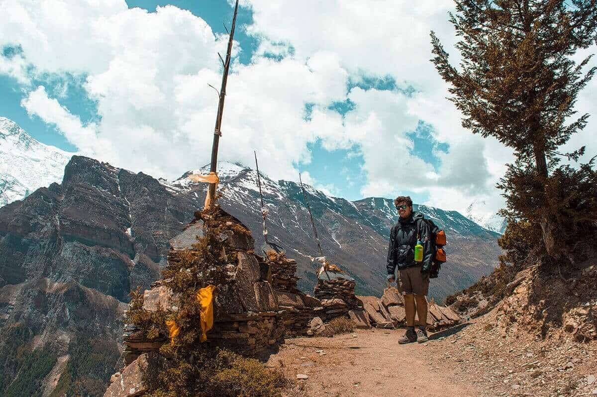 james hiking the annapurna circuit with snowy mountains in the backdrop