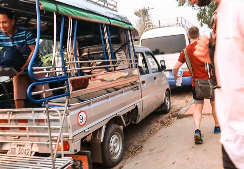 jumping out of a tuk tuk while backpacking luang prabang