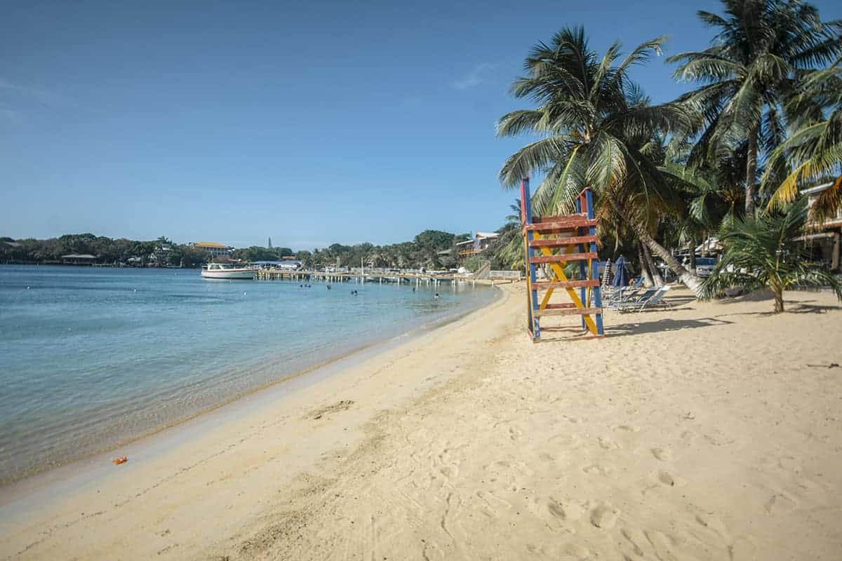 a colorful lifeguard tower on the sandy shores of half moon bay in roatan