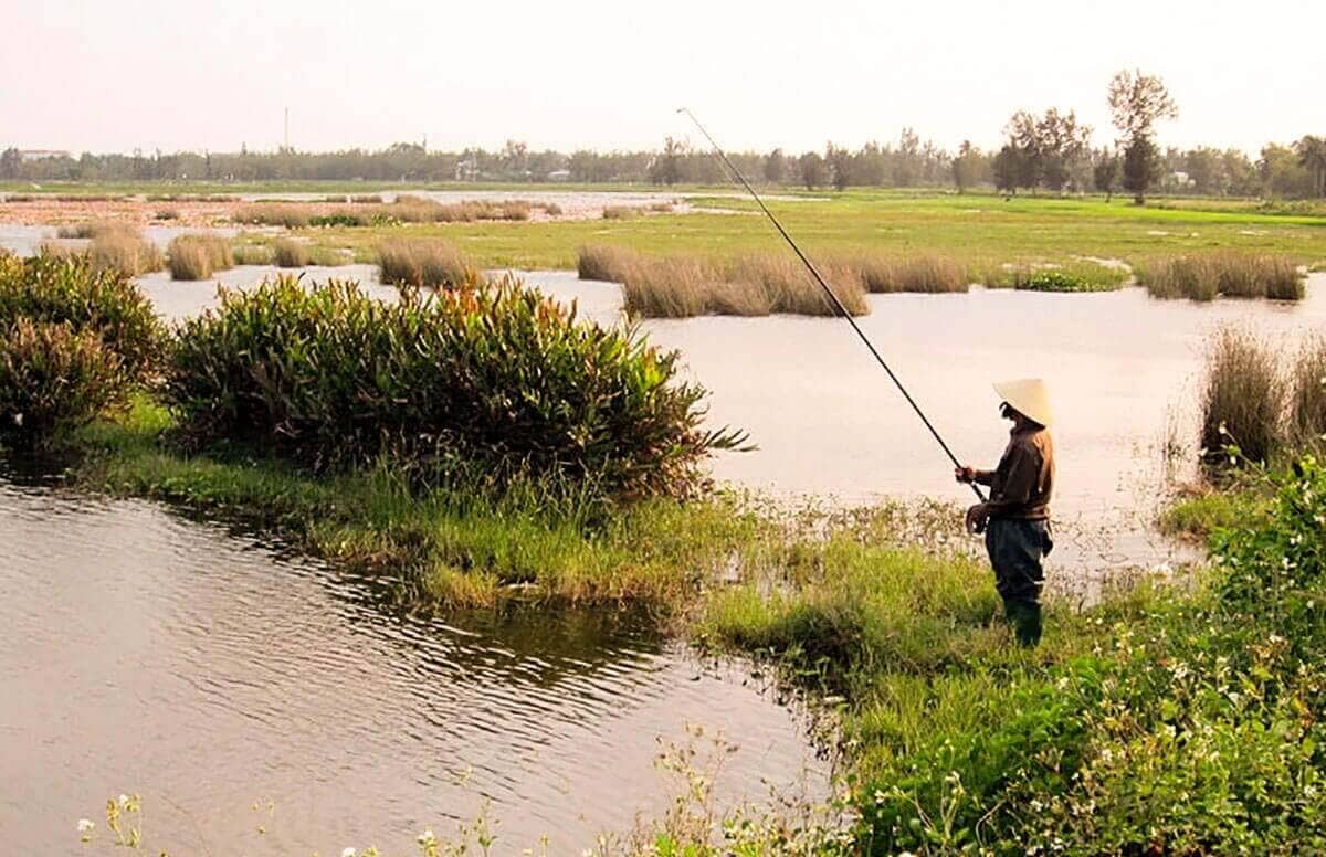 fisherman standing in waterway at cam kim vietnam