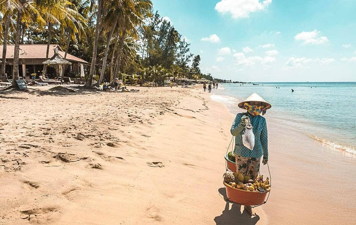 vietnamese lady holding basket of fruit at beach in phu quoc