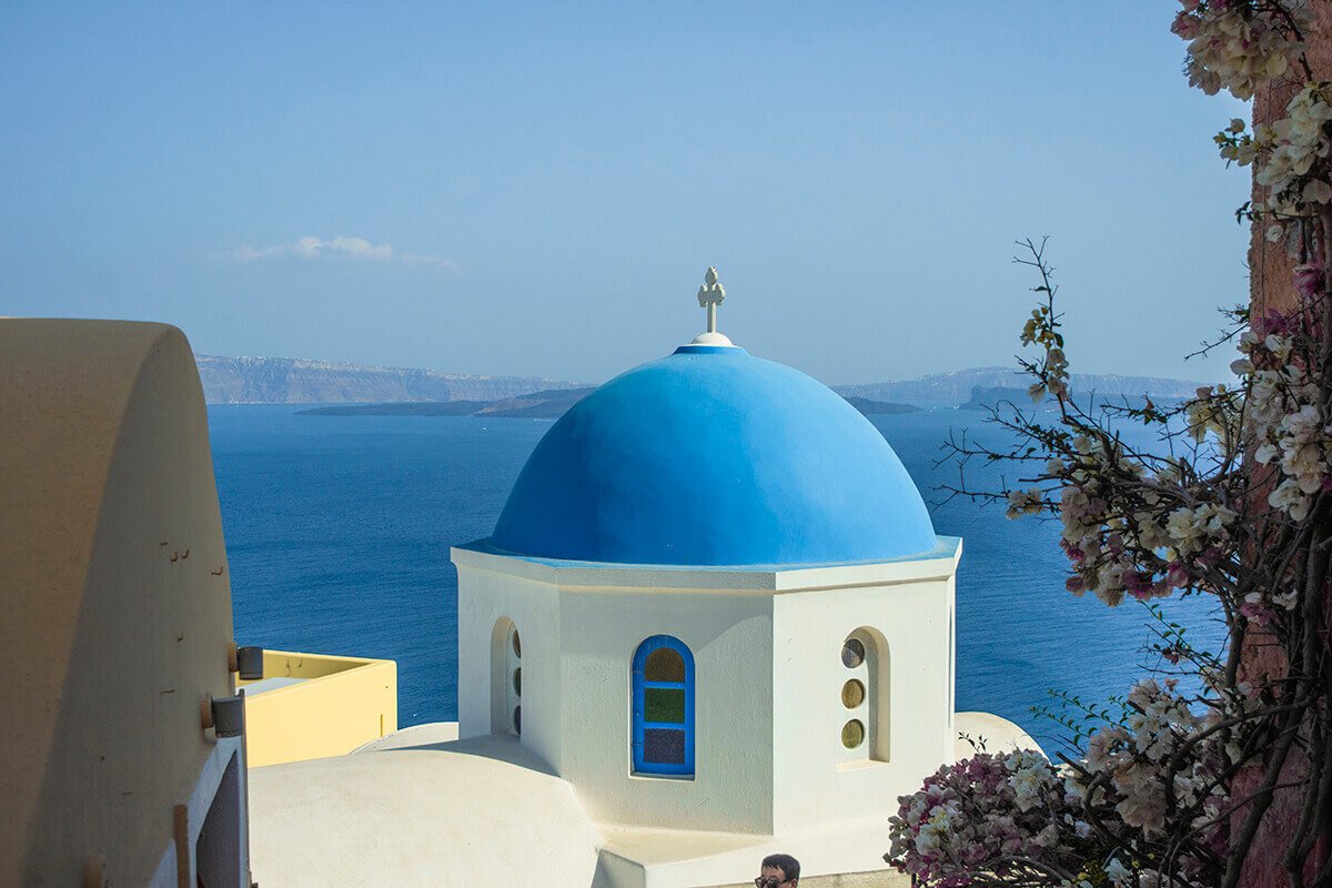 flowers and blue church in oia sightseeing santorini