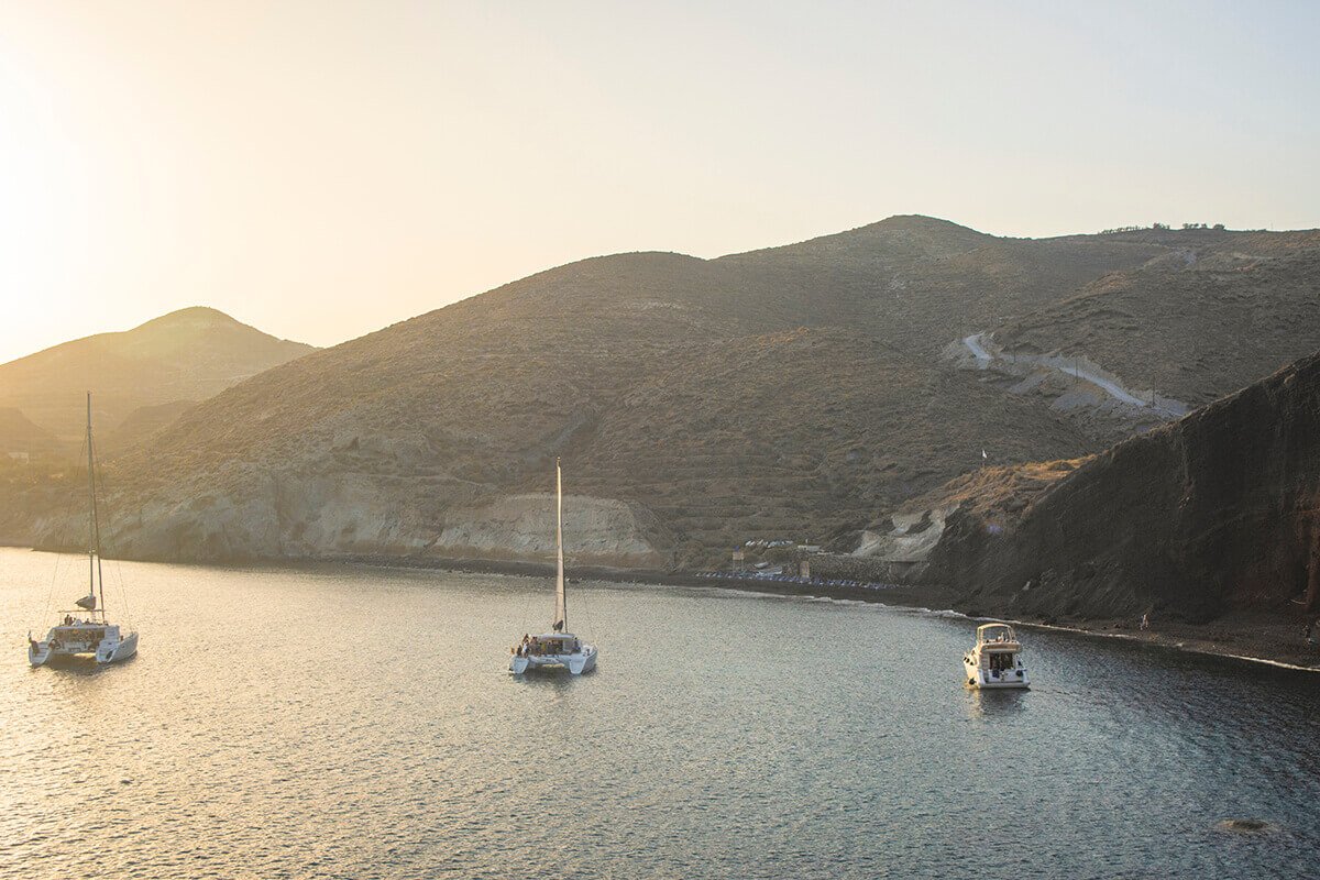 red beach in santorini with boats