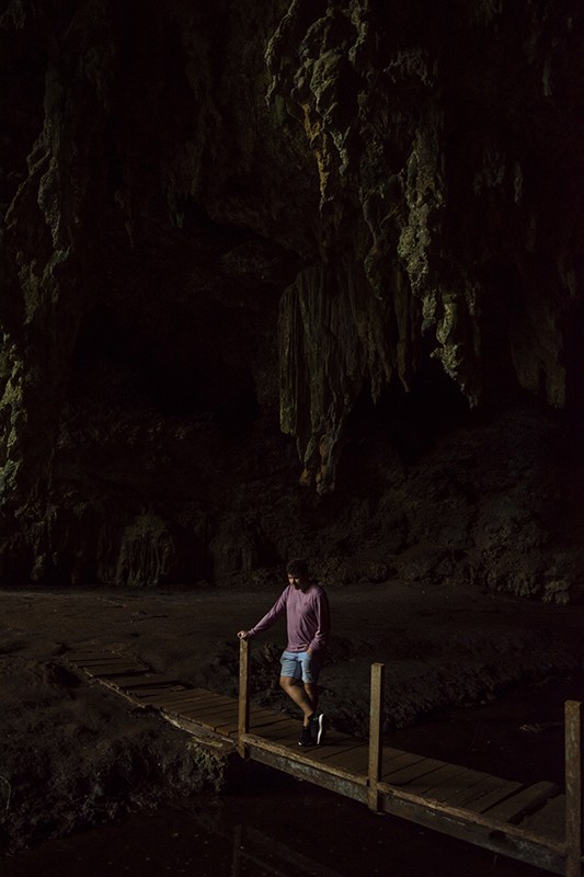 Queen Hortense's Cave In The Isle Of Pines: BEST Tips 2025 7 A man standing on a wooden bridge in front of Queen Hortense’s Cave on the Isle Of Pines.