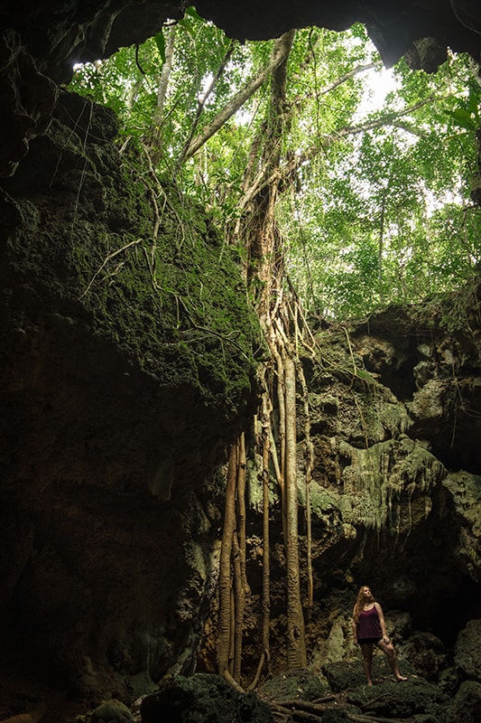 Queen Hortense's Cave In The Isle Of Pines: BEST Tips 2025 9 A woman standing in Queen Hortense’s Cave with a tree growing out of it.