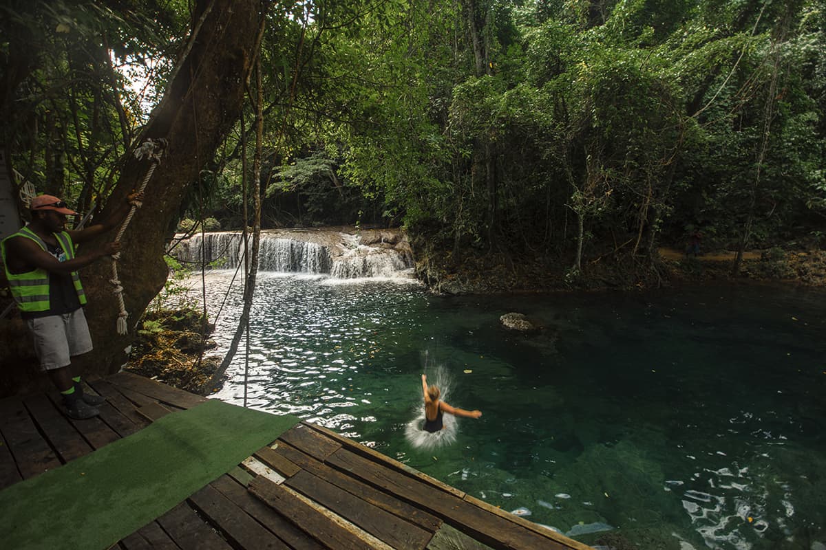 a women splashing into the water at rarru cascades after jumping off one of the platforms