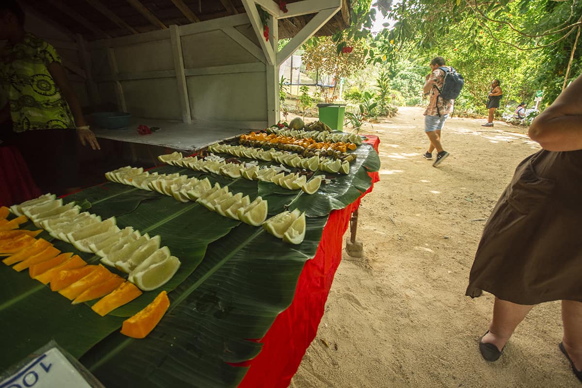 a table of fruit laying out at the entrance of rarru cascades