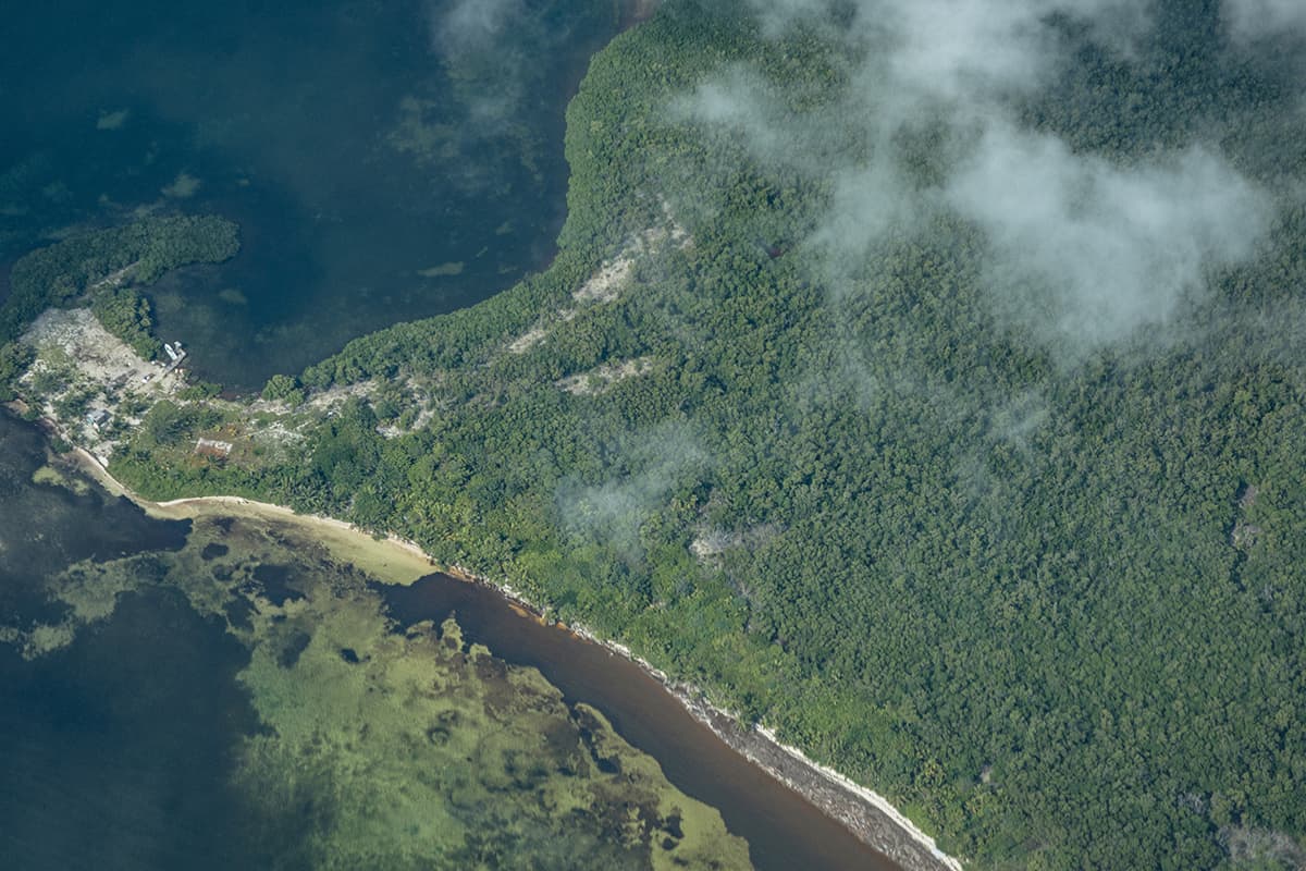 looking down on small buildings and jungle on a large island in belize
