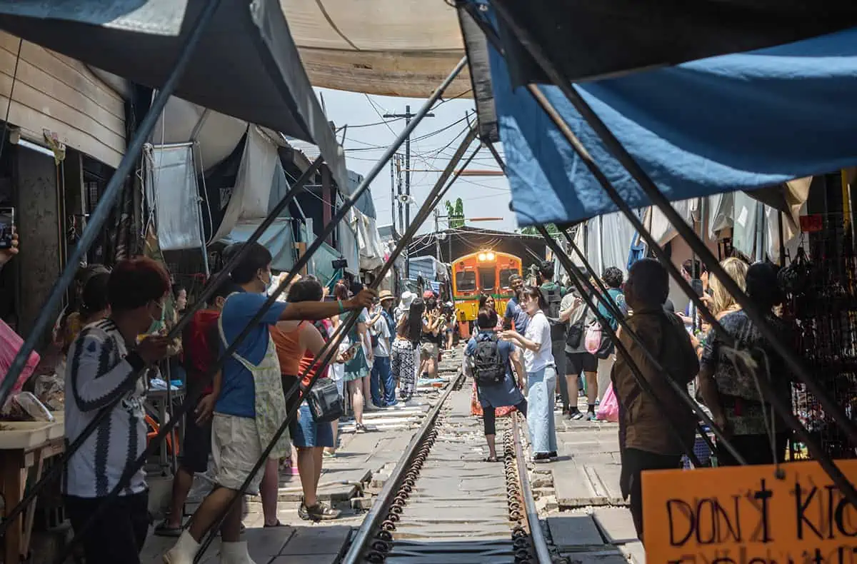 watching the train come through the maeklong railway market with sellers about to pull back the awnings