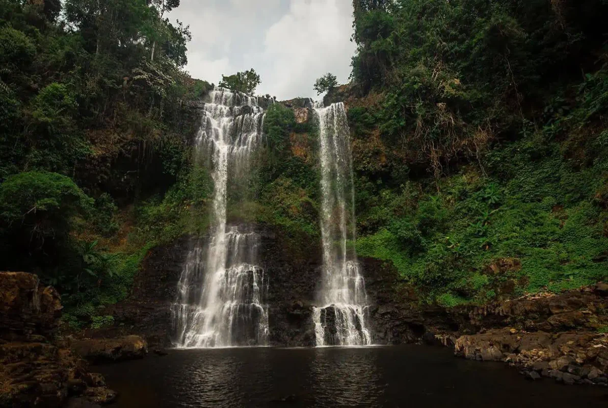 double falls flowing into a pool at tad yuang waterfall in pakse, a must visit on the 2 week in laos itinerary
