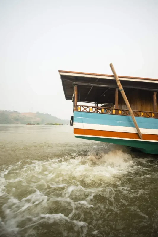 the back of a slow boat with its motor whirling in huay xai