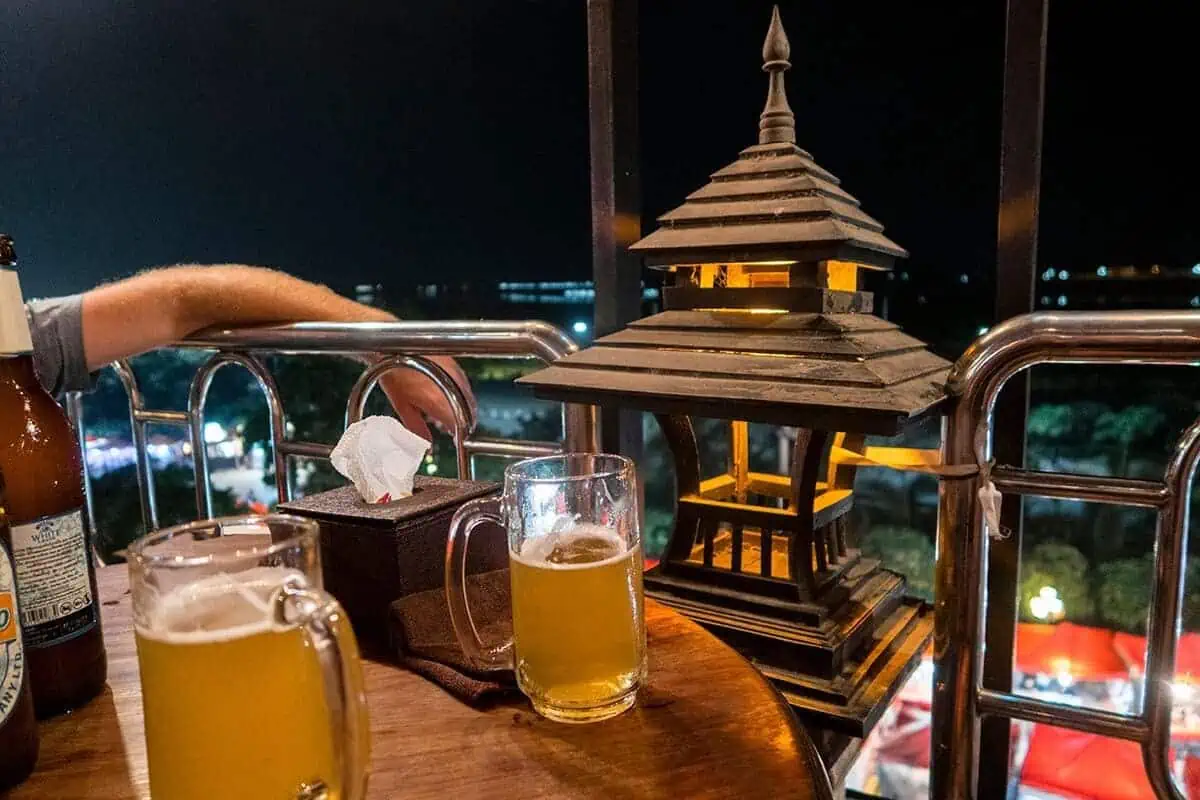 having beers from a rooftop bar in vientiane during the evening with a night market below
