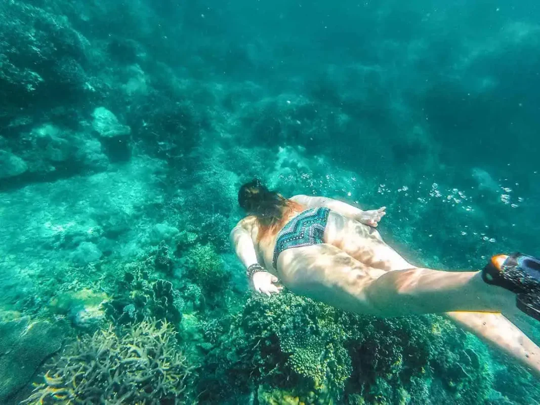 Snorkeler exploring vibrant coral reefs beneath Vietnam's clear blue waters, an underwater escapade for any Vietnam itinerary.