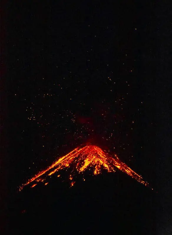 rocks and lava flying up into the night sky