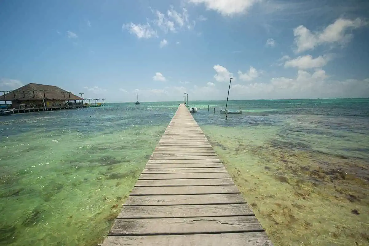 A wooden pier stretching into the clear Belizean waters of Ambergris Caye, a contrast to the intimate docks of Caye Caulker.