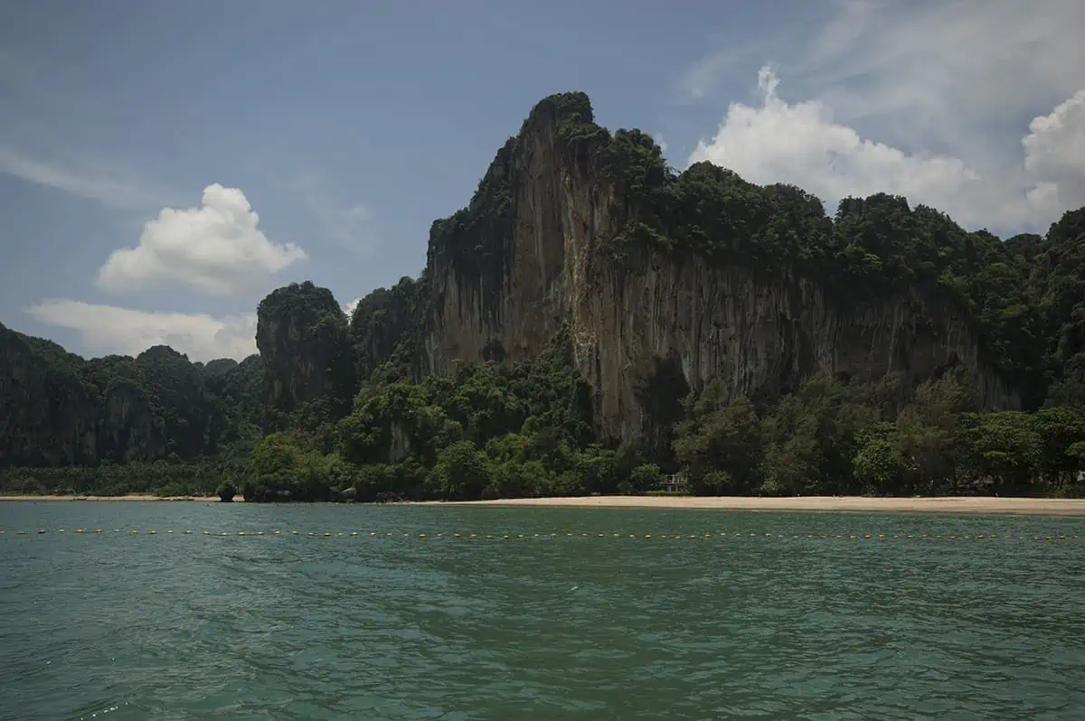 Ao Nang To Railay Beach: The ULTIMATE Guide 2025 11 View from the water looking toward Railay Beach, showing a long stretch of shoreline roped off from long tail boats for swimmers
