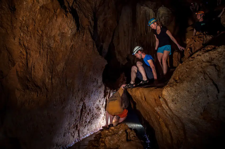 climbing down a section of rocks into the river on the atm cave tour