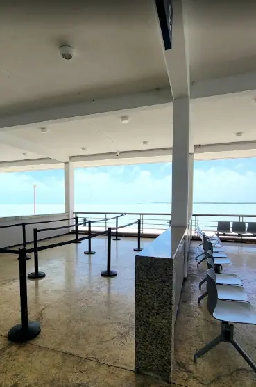 An empty waiting area at a ferry terminal in Chetumal, with stanchions guiding passengers and metal chairs arranged in rows. 