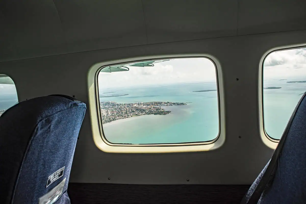 View from an airplane window showcasing the coastal landscape near Belize airport, with a clear view of the shoreline and scattered islands, before starting our journey from belize airport to san ignacio