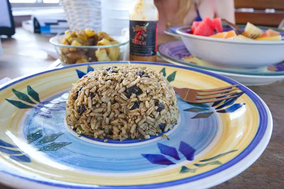 Belizean rice and beans, a staple for breakfast in Belize, served on a vibrant plate alongside tropical fruits, showcasing the simplicity of local flavors