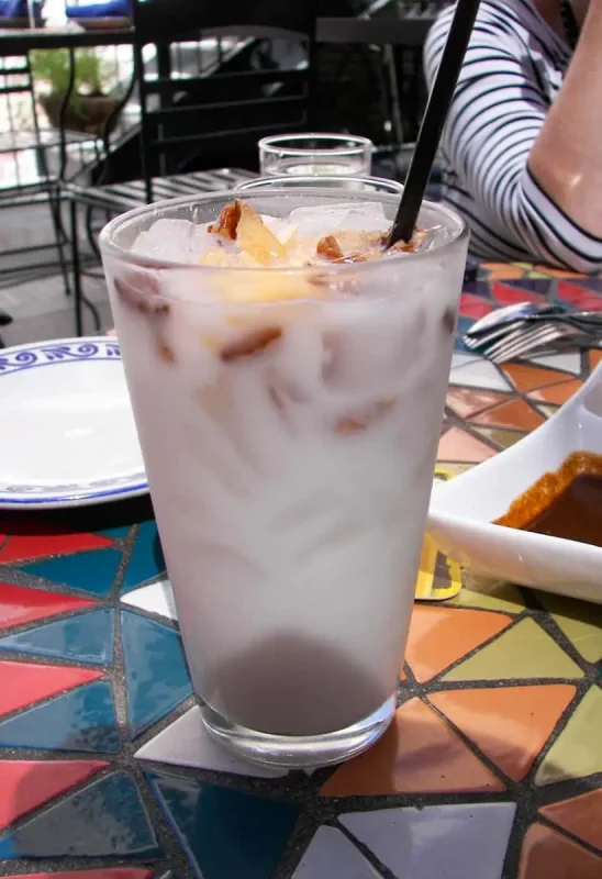 Close-up of a refreshing glass of iced horchata, a popular drink to accompany a Belizean breakfast, served at a colorful tiled table.