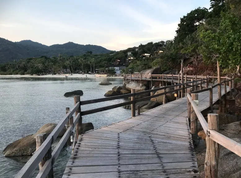walking a;long the wooden pathway at dusk on leela beach koh phangan