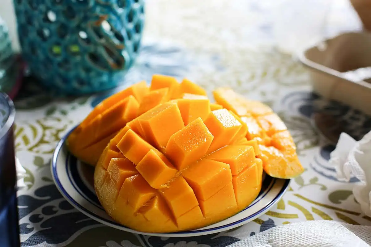 A ripe mango artfully cut in a grid pattern on a plate, ready to be enjoyed, showcasing a popular way to eat this sweet fruit.