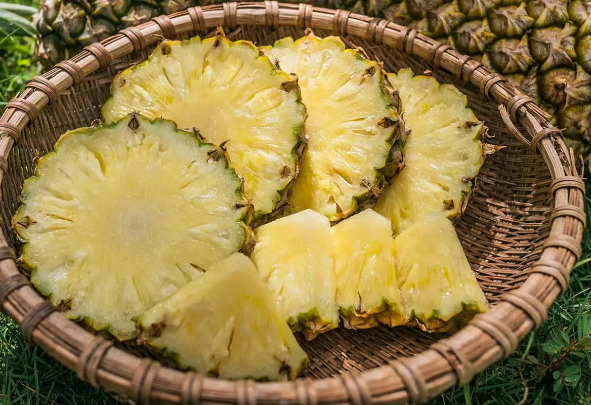 Freshly cut pineapple slices arranged in a woven basket, emphasizing the juicy, tropical flavor.
