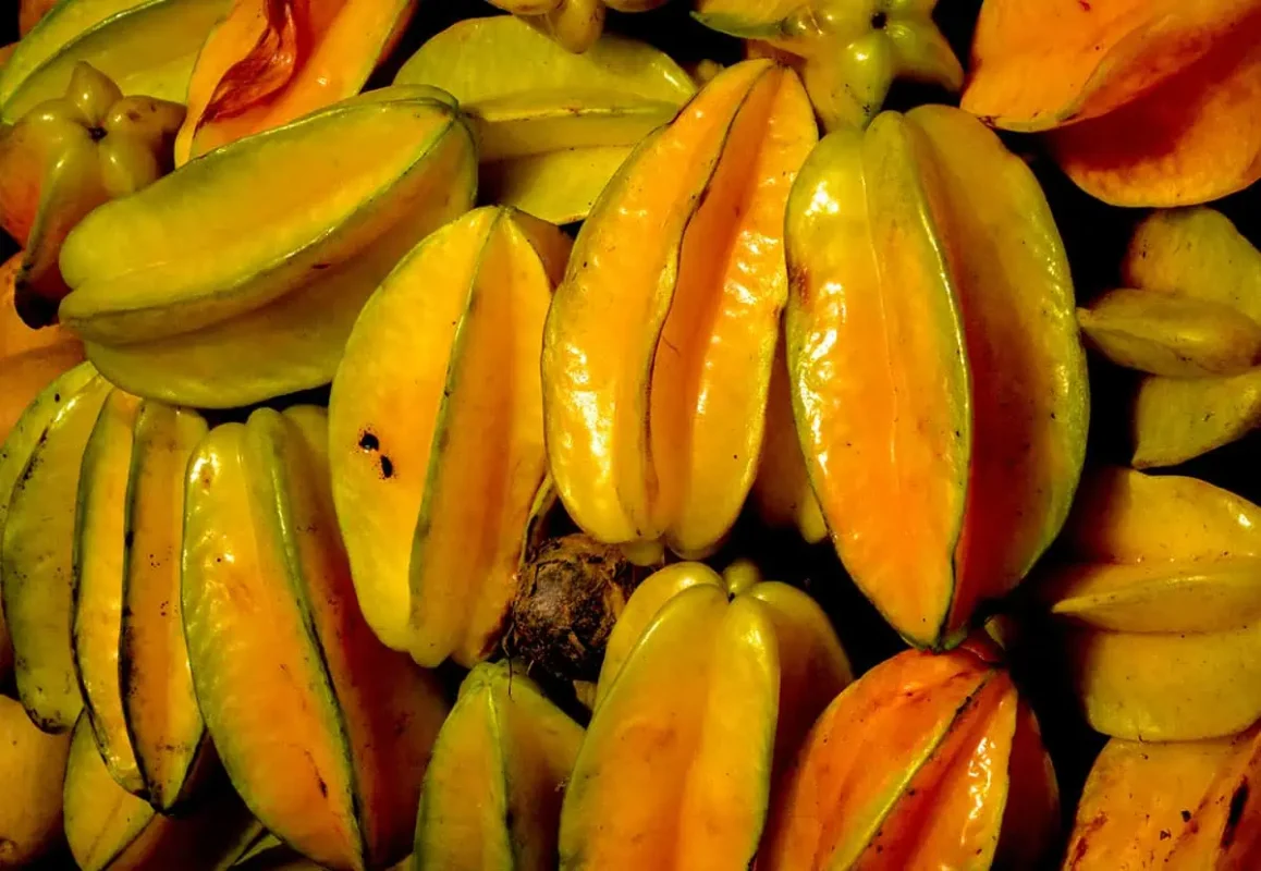 Pile of yellow-orange star fruits, also known as carambola, a tropical fruit that is commonly enjoyed in Belize for its sweet and tangy flavor.