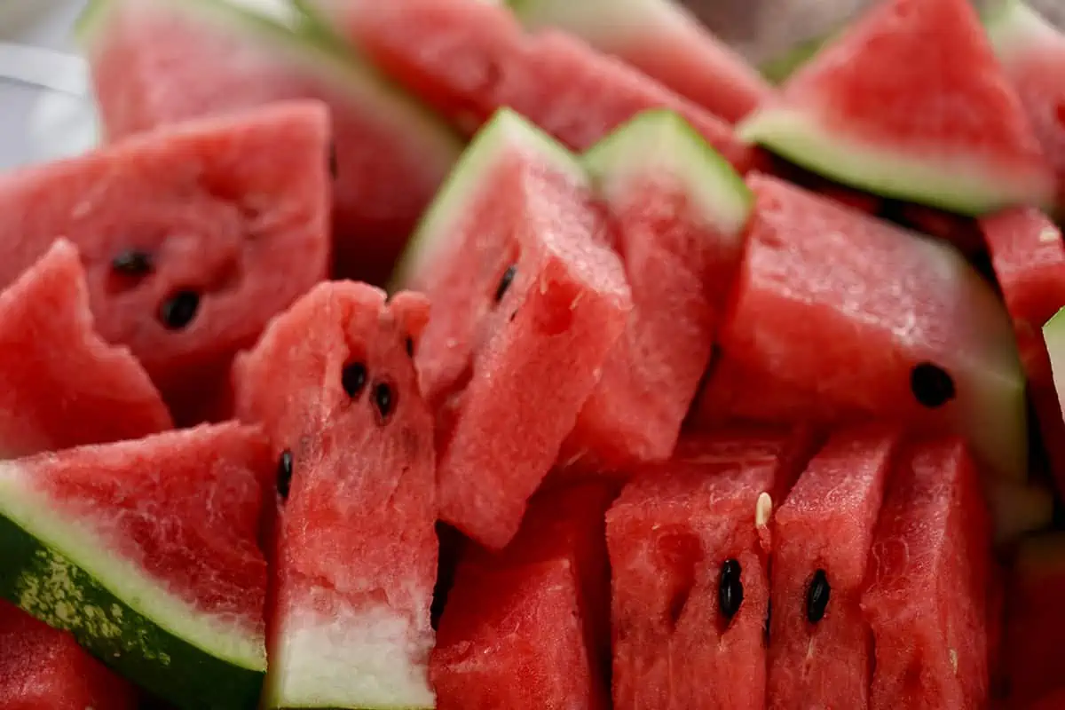 Slices of juicy red watermelon arranged with precision, showcasing the refreshing summer fruit with black seeds.