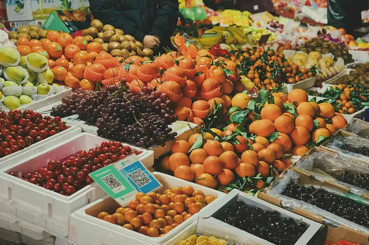 A vibrant array of fruits for sale at a market, featuring oranges, kiwis, grapes, and strawberries, showcasing the diversity of fruits in Belize.