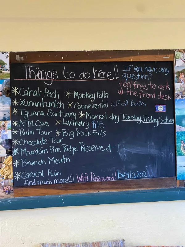 A chalkboard at Bella's Backpackers listing 'Things to do here' with various local attractions and hostel amenities, useful for guests seeking the best experiences in San Ignacio.