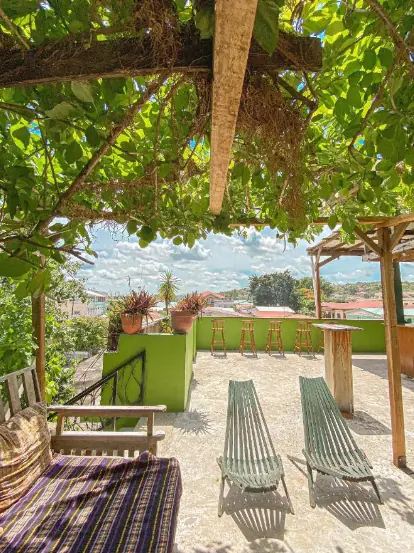 A sunny rooftop terrace at Bella's Backpackers, displaying comfortable seating and lush greenery, inviting guests to relax and socialize in one of San Ignacio's top hostels.