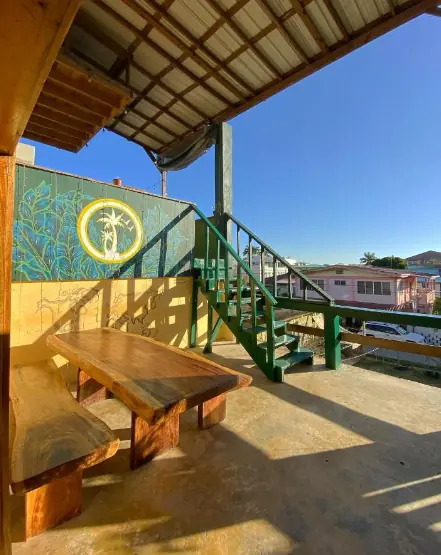 A view of Bella's Backpackers' outdoor seating area with wooden benches and a mural, exemplifying the creative and inviting communal spaces at a leading San Ignacio hostel.