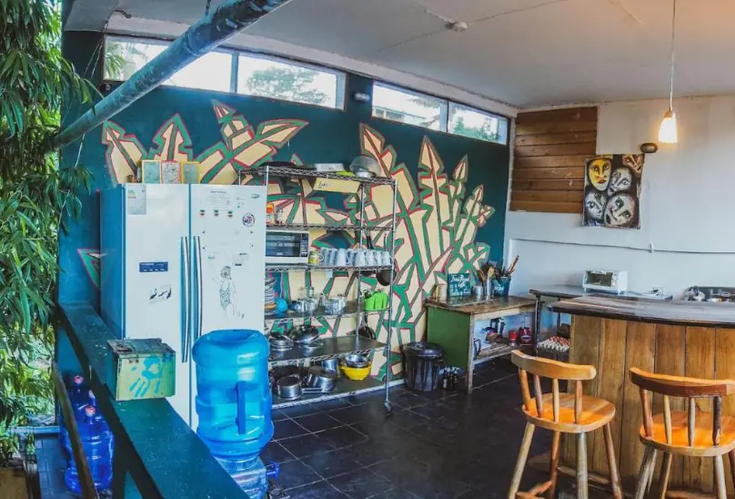 A communal kitchen area inside Bella's Backpackers, adorned with colorful murals and fully equipped for guest use, illustrating the convenient facilities at this top-rated San Ignacio hostel.