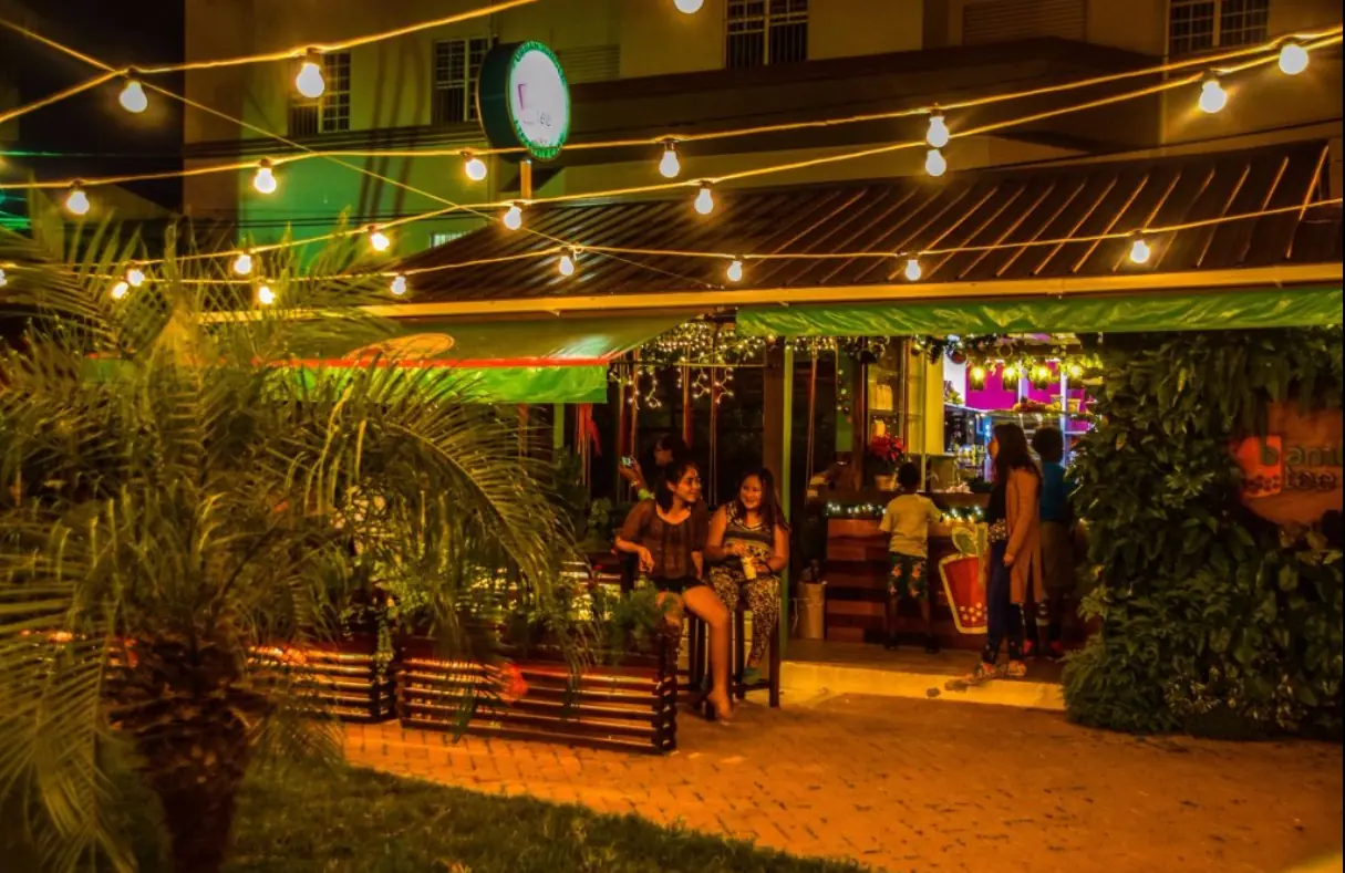 Warm, inviting ambiance of a restaurant at night with string lights, tropical plants, and guests dining al fresco, a cozy dining spot in San Ignacio.