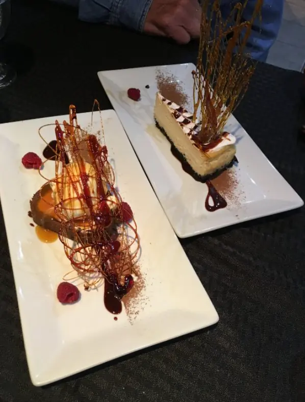 An elegant dessert presentation featuring a slice of cheesecake with a caramel spiral decoration, showcasing the culinary creativity found in San Ignacio, from crave house of flavors