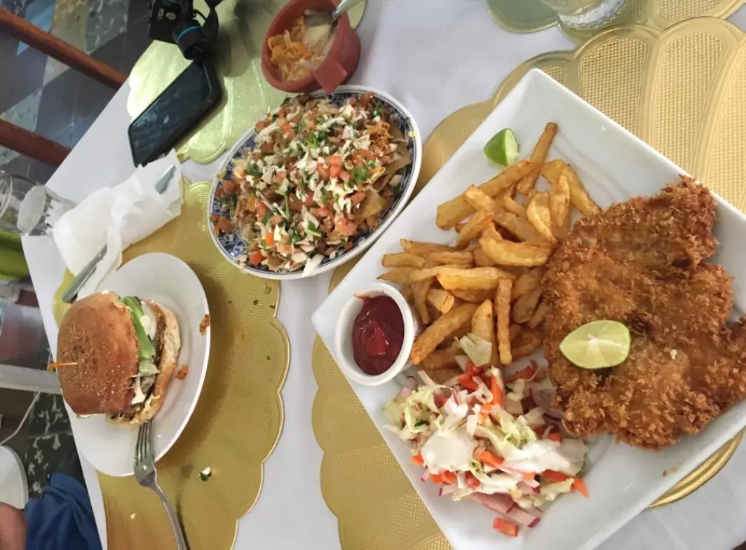 A casual dining spread with a burger, chicken schnitzel with fries, and a loaded seafood ceviche, exemplifying the diverse food options in San Ignacio from ervas restaurant