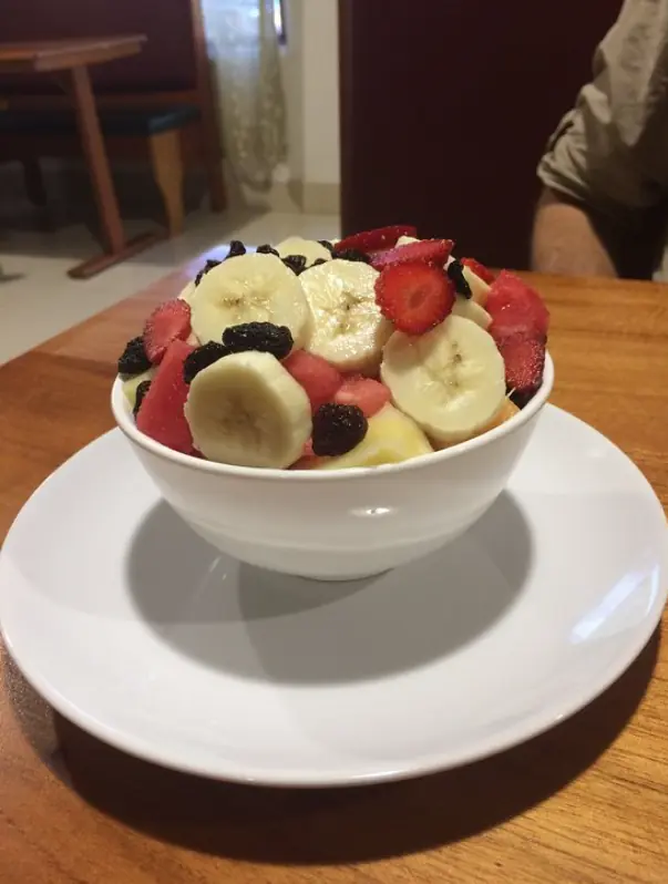 A healthy bowl of fresh fruit salad with banana, strawberry, and raisins, a light and nutritious option when wondering where to eat in san ignacio