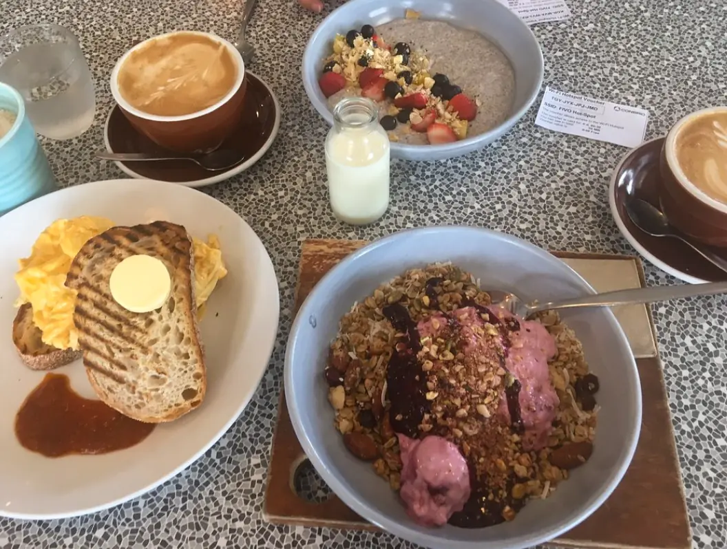 A hearty breakfast spread with scrambled eggs on toast, oatmeal with fruit, and a cappuccino, typical of the morning offerings at the shack cafe, one of best restaurants in San Ignacio.