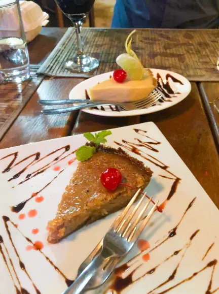 Best Restaurants In San Pedro Belize For Breakfast, Lunch & Dinner 17 An elegant dessert course at Aji Tapa Bar & Restaurant, capturing a slice of velvety walnut pie and a creamy cheesecake garnished with a lime slice and cherry, representing the fine desserts available at restaurants in San Pedro Belize.