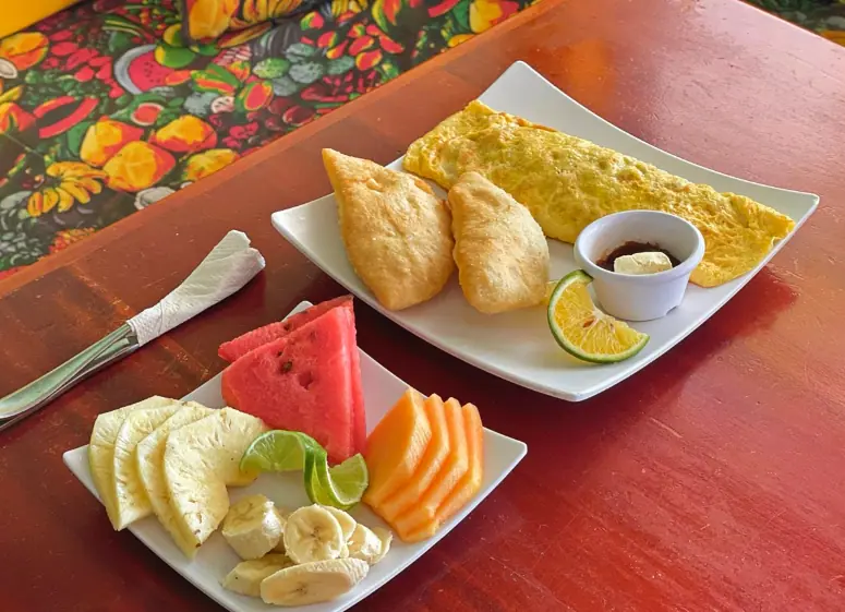 Best Restaurants In San Pedro Belize For Breakfast, Lunch & Dinner 6 A colorful local breakfast plate from lilys treasure chest featuring a fluffy omelette, golden fry jacks, and slices of fresh watermelon, pineapple, and banana, capturing the essence of traditional morning meals at restaurants in San Pedro Belize.