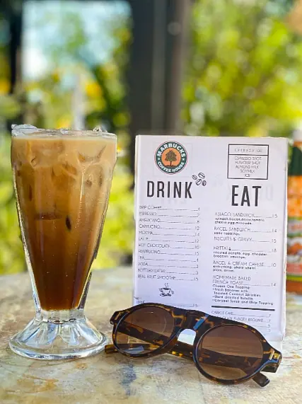 Best Restaurants In San Pedro Belize For Breakfast, Lunch & Dinner 8 A relaxed outdoor setting at Marbucks Coffee House with a refreshing iced coffee and a menu listing delicious offerings, embodying the laid-back atmosphere of San Pedro Belize's favorite coffee spots.