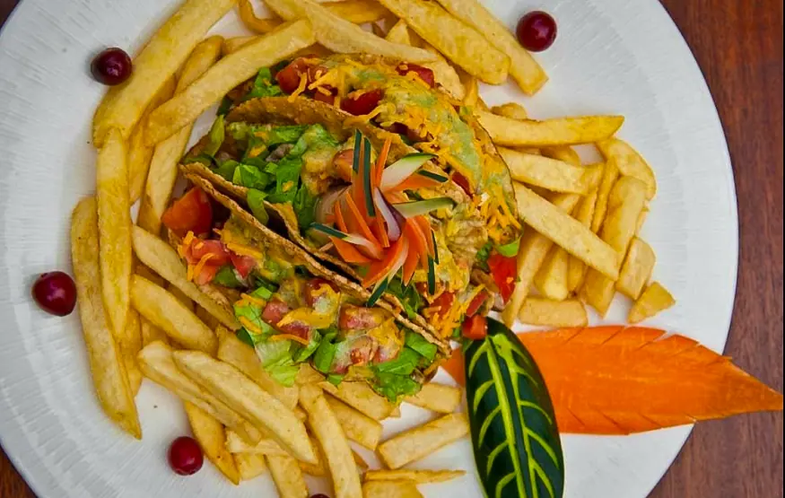 Best Restaurants In San Pedro Belize For Breakfast, Lunch & Dinner 15 A savory chicken taco salad surrounded by golden French fries, artfully presented on a white plate, exemplifying the fusion of local flavors with international fare at Pineapples Restaurant, one of the best restaurants in san pedro belize