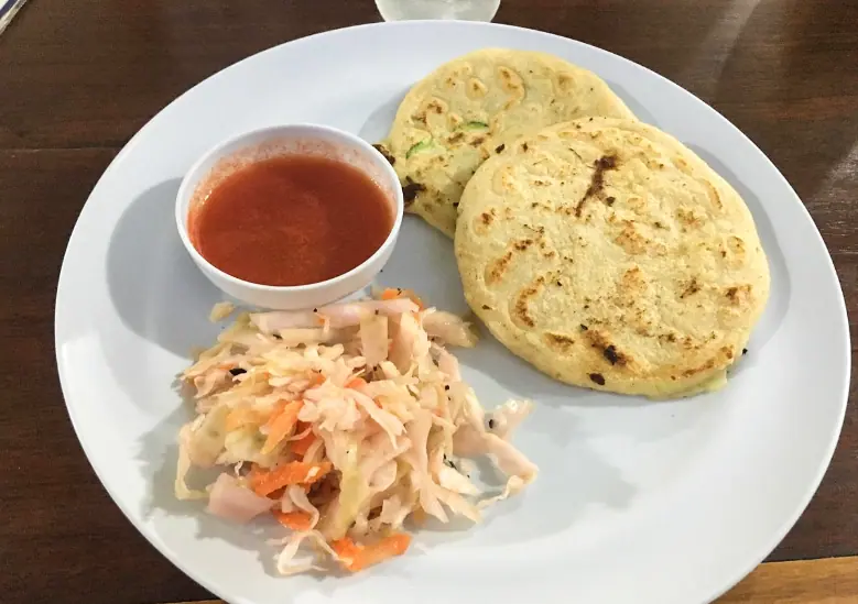 Best Restaurants In San Pedro Belize For Breakfast, Lunch & Dinner 13 A traditional plate of pupusas from Waruguma in San Pedro Belize, served with a side of tangy cabbage slaw and tomato sauce, showcasing the authentic and popular street food available in the area.