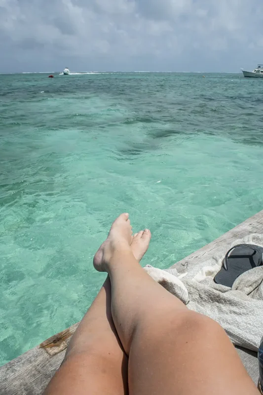 tasha amy relaxing on a dock with feet extended, showcasing the laid-back lifestyle and the simple pleasure of enjoying the crystal-clear waters of Ambergris Caye.