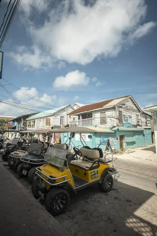 Golf carts parked along a sandy road in Ambergris Caye, indicative of the primary mode of transportation for locals and tourists alike.