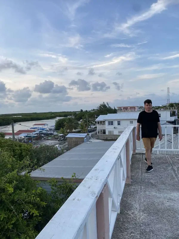 A man walking along the rooftop with a view of Ambergris Caye, providing a perspective on the laid-back island lifestyle and the simplicity of enjoying beautiful vistas.