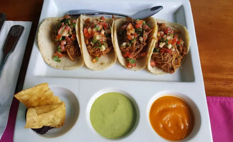 Delicious and authentic Belizean tacos served with sides of guacamole and spicy sauce, representing the culinary delights that await visitors looking for the best things to do in Ambergris Caye.